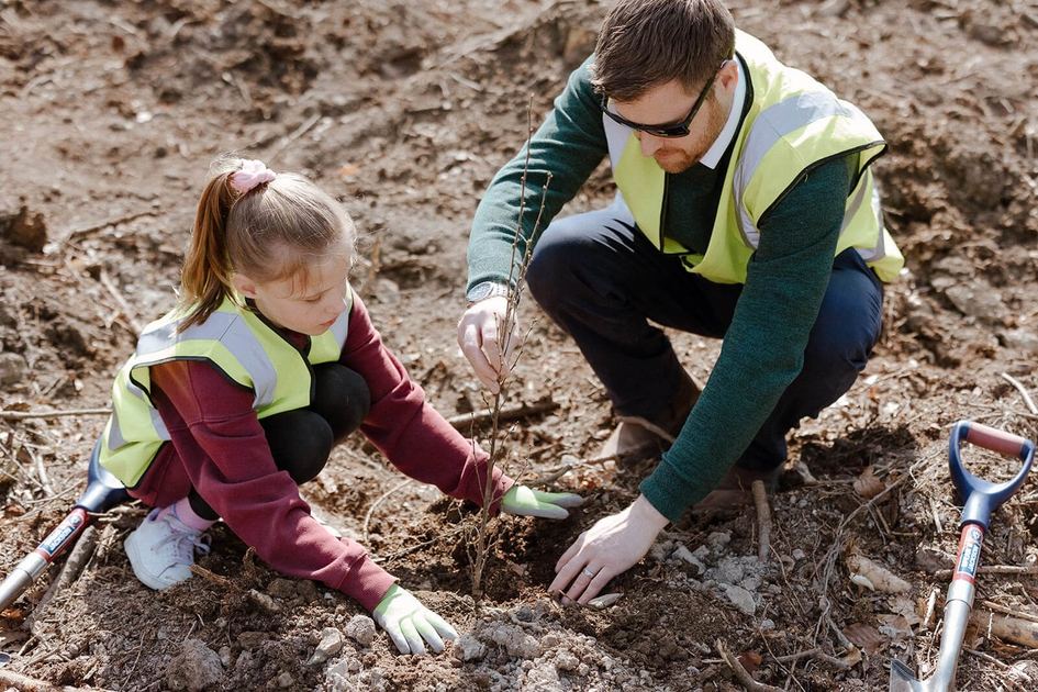 A girl and a volunteer planting a tree
